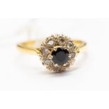 A sapphire and diamond cluster ring the central round cut sapphire within a border of old cut