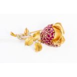 A ruby and diamond brooch in the form of a rose bud, the bud set with round cut rubies,