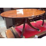 A reproduction yew oval coffee table with a pedestal support and four sabre legs with metal castors.