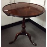 A George III mahogany tripod table, the single plank top with a dished edge,