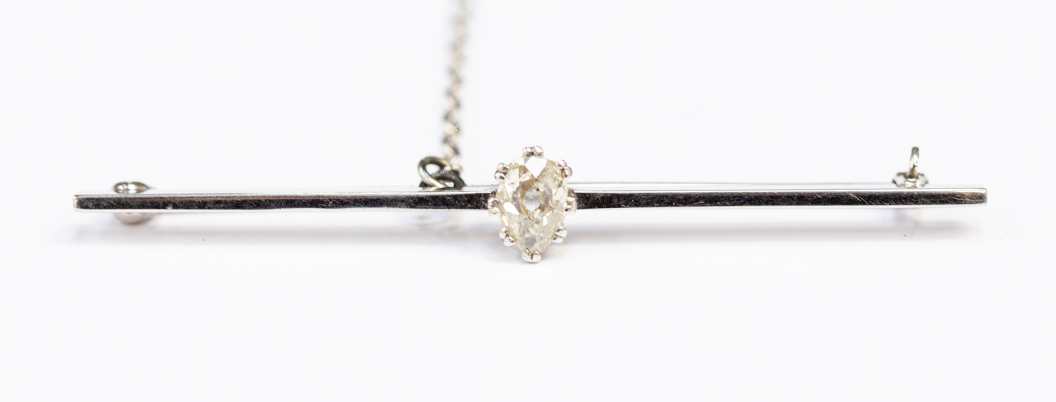 A diamond set bar brooch, the claw set pear cut diamond claw set to the centre weighing approx 0.