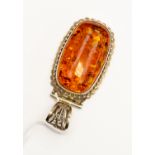 An amber and silver pendant, elongated amber with fancy silver border,