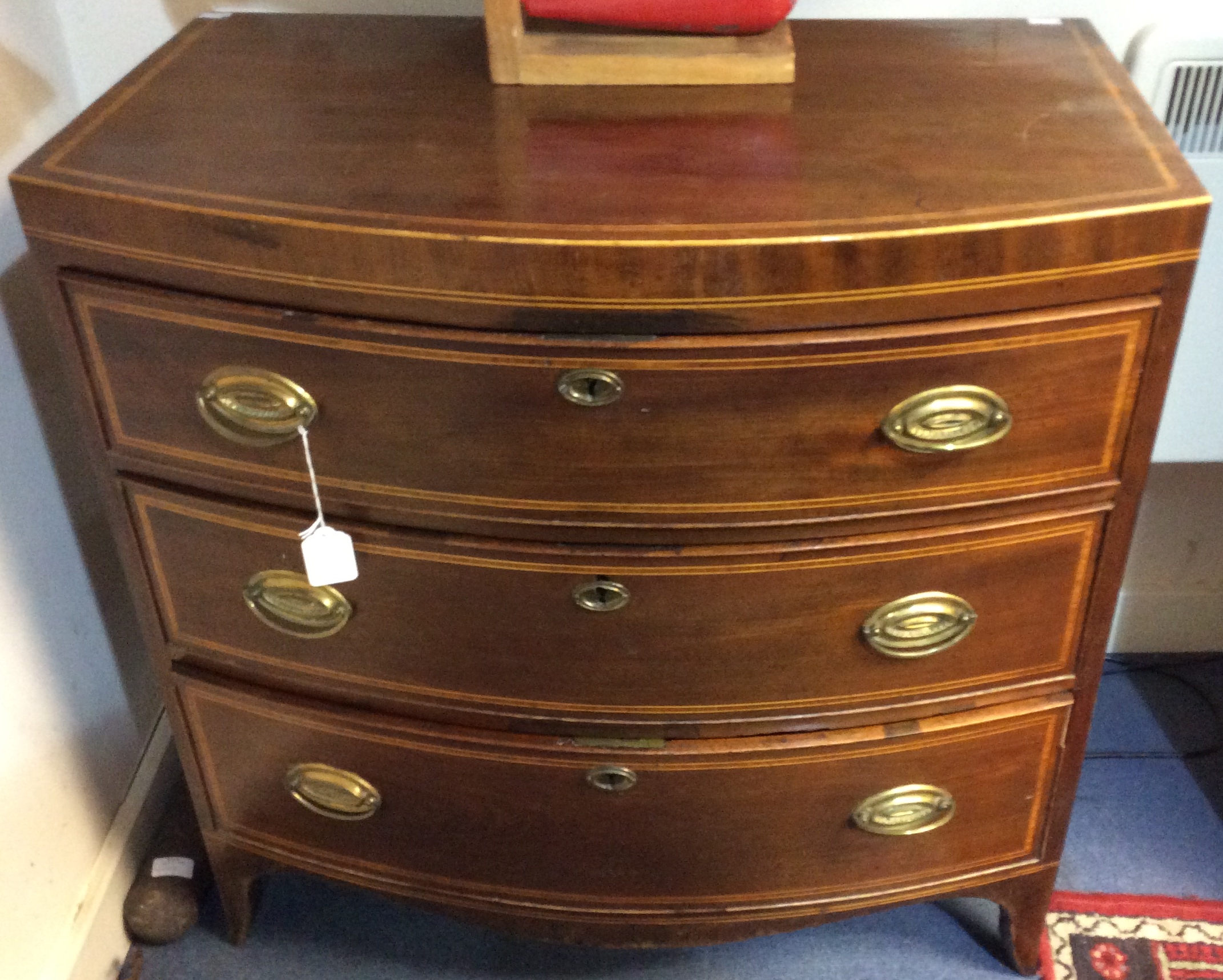 A George III mahogany bow fronted chest of drawers, fitted with three graduated drawers,