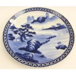 A 19th century Japanese Arita large blue and white charger decorated centrally with a mountainous