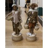 A pair of Royal Dux Arabian water carrier figures, standing on tall plinth bases,