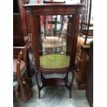 An Edwardian mahogany, oval form, glazed display cabinet with two glass shelves,
