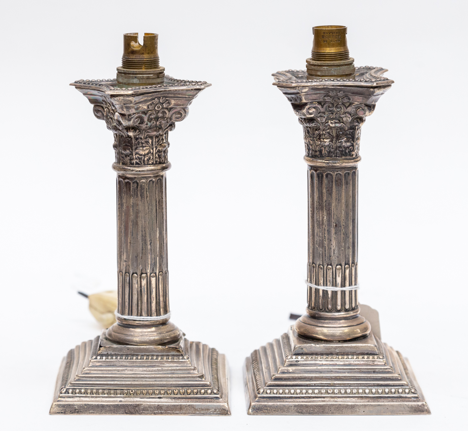 A pair of George V silver Corinthian column electrical candlesticks converted to lamp bases,