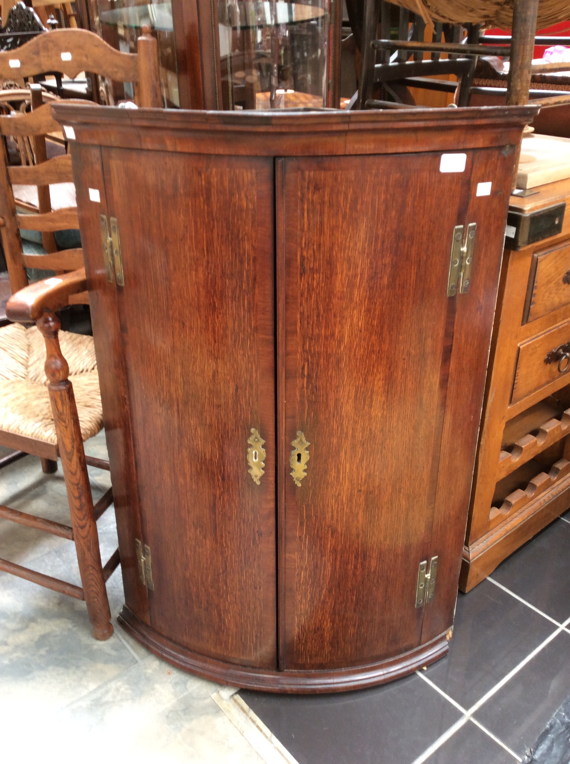 A Georgian bow fronted corner wall cabinet with double doors and three shelves inside