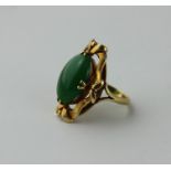 An 18ct. yellow gold and jade dress ring, having undulating open work 'tied ribbon' form mount