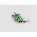 A 14ct. yellow gold and jade brooch, fashioned as a stylised flower, claw set eight oval and tear