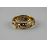 A yellow metal hinged circular bangle, set numerous round cut clear stones and various coloured