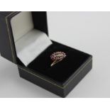 A 10ct. yellow gold, ruby and diamond dress ring, in the cross-over style, the ovoid mount set row
