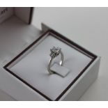 An 18ct white gold three stone diamond ring, the centre set emerald cut diamond flanked by two round