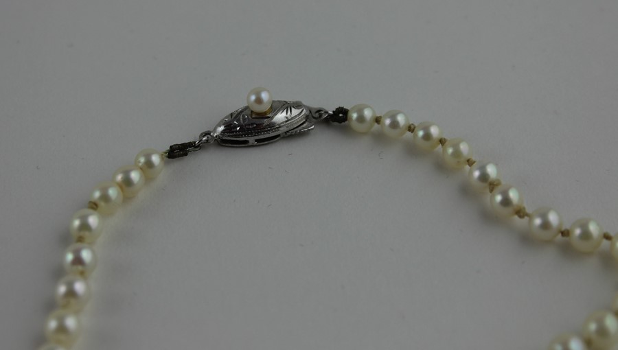 A graduated cultured pearl necklace, to white metal clasp set single pearl, impressed "silver", - Image 2 of 3