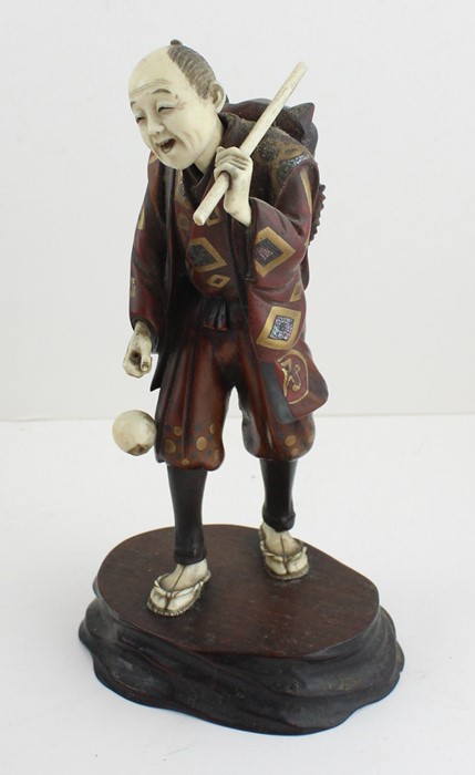 A Japanese Meiji period Okimono depicting a travelling entertainer , red seal mark to base