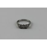 A platinum and three stone diamond ring, set row of three graduated diamonds, the largest to