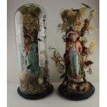 A pair of early 20th Century Bisque figurines, housed in original domed cases (one lacking glass).