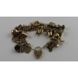 A 9ct. yellow gold curb link charm bracelet suspending an extensive collection of gold charms,