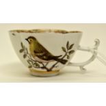 A Meissen shaped teacup depicting a bird on a branch, gilded rim,