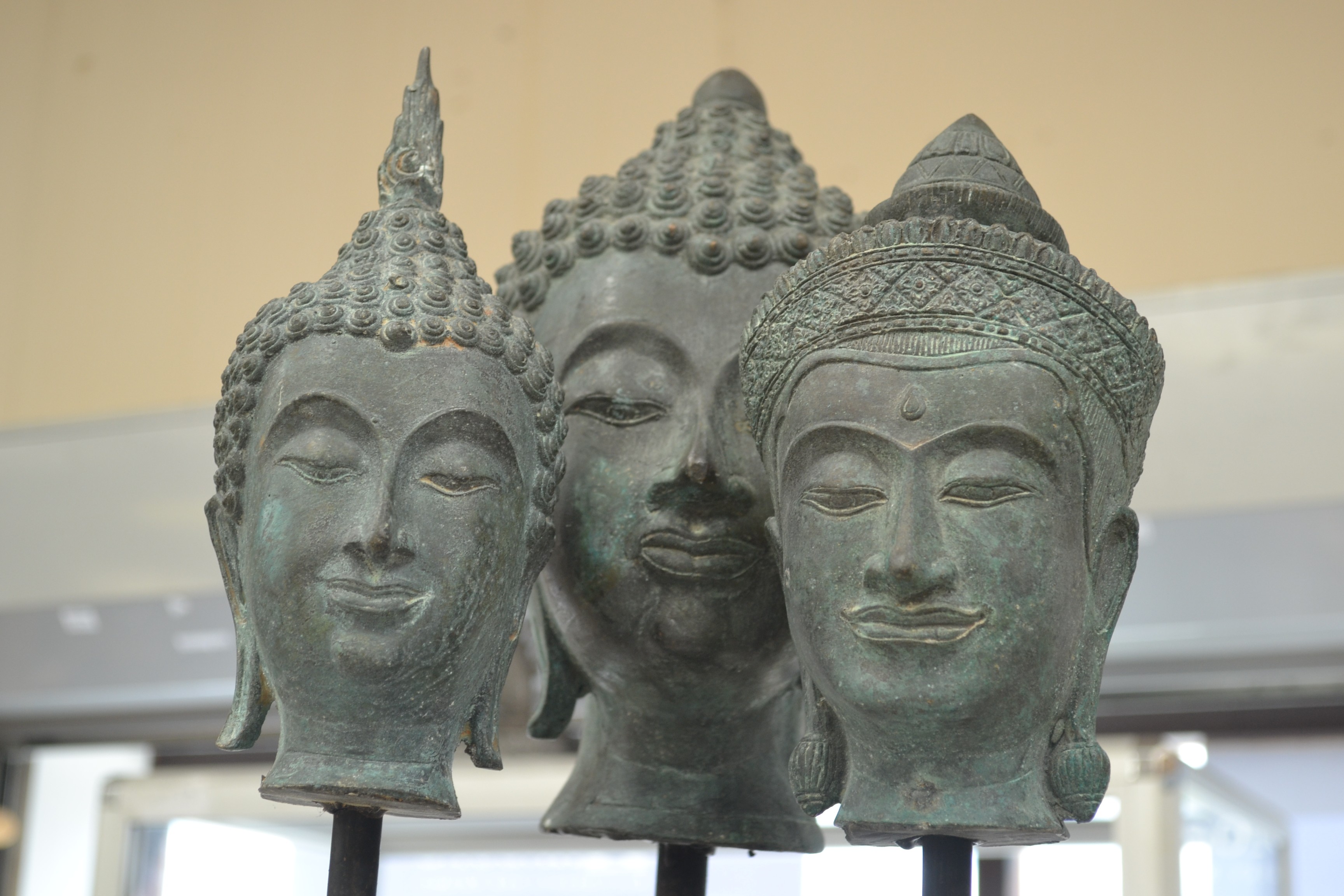 Three 20th Century Buddha's heads on stands