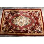 A Chinese style woollen rug, red ground with gold border,