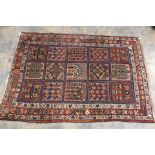 A hand knotted woollen rug with a red, blue and cream background,