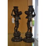 A pair of 19th Century bronze figural candlesticks, raised on circular socles,