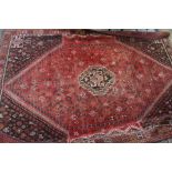 A large mid 20th Century hand knotted rug with a red and brown ground,