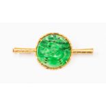 A Chinese style unmarked yellow metal brooch, circular green carved detail to the centre,