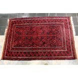 Woollen hand knotted rug with red ground and black middle eastern influence.