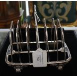 A William IV silver seven bar toast rack, loop handle raised on four paw and floral feet, London,