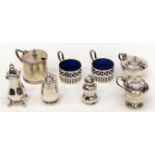 A collection of various silver condiments including three peppers,
