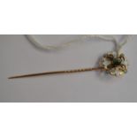 An enamel stick pin, open work finial set to the centre with a star stone,