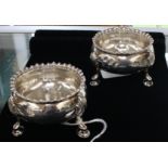 A pair of George II silver circular salts, raised gadroon border on three shell and hoof feet,