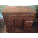A George I style walnut kneehole desk, comprising one long drawer, frieze drawer, six small drawers,