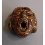 A treacle glazed inkwell pen holder n the form of screaming face, circa 1900, 6cm by 6cm, 4cm high