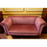 An early 20th Century upholstered settee, standing on square tapered legs with castors