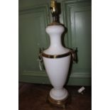 An opaque white glass table lamp, with brass handles and rings.