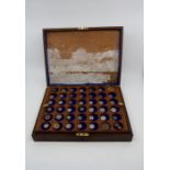 A wooden case containing a collection of coins and medallions in three trays, may have been turned