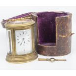 An oval carriage clock, with case and key, the glass to the clock bevelled, the metal surround is