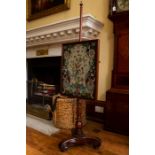 A Victorian pole screen, the panel with woolwork design, raised on a turned column, standing on a