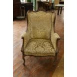 A late 19th Century French wing back armchair, scrollwork carved wooden frame, damask upholstery,