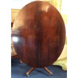 An early 19th Century rosewood tilt-top breakfast table, oval top, having a turned column, four