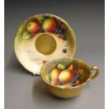 A Royal Worcester tea cup and saucer painted with fruit, he outside is solid gilding, signed Austin,