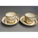 Two Derby tea cups and saucers, each with floral painted panels within gilt cartouches and gilt