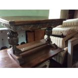 An early 20th Century oak draw-leaf dining table, raised to each end on a carved cup and cover