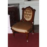 A late Victorian upholstered armchair, with an arched shaped crest rail, deep button backed seat