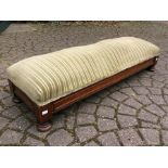 An Edwardian mahogany footstool, having a sprung seat, raised on bun feet