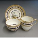 A Derby trio of coffee cup, tea bowl and saucer, each painted with rural landscapes attributed to