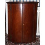 A George III mahogany bow fronted hanging corner cupboard